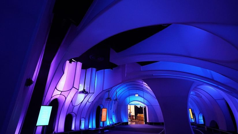 Curved architectural interior lit with vibrant purple and blue lights, creating a futuristic atmosphere.