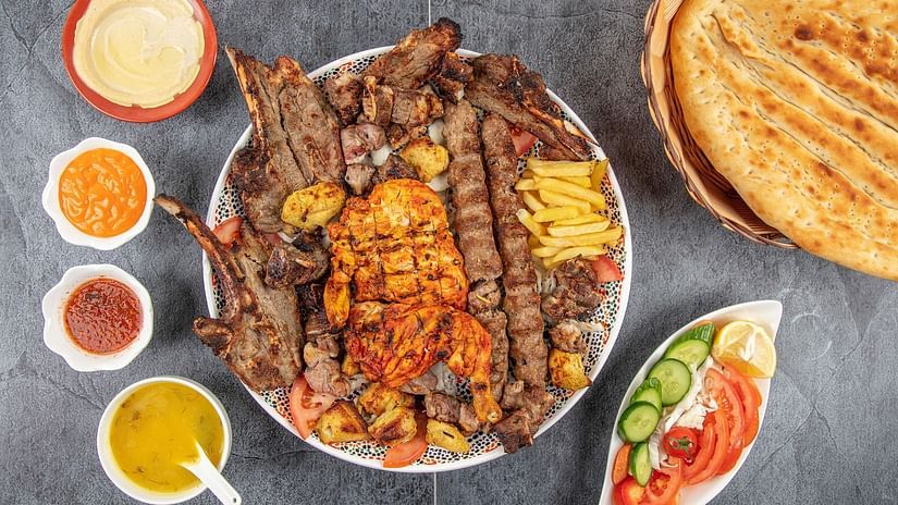 A mix grilled kebab platter with different sauces on the side
