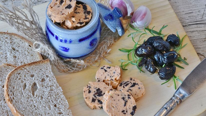 high tea setup with an elegant blue tea pot bread and butter on the side accommpanied by some blue berries.