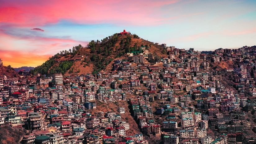 Several houses crowded on a mountain beneath the pink sky