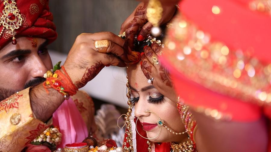 a groom putting vermilion on his bride's forehead during their wedding ceremony