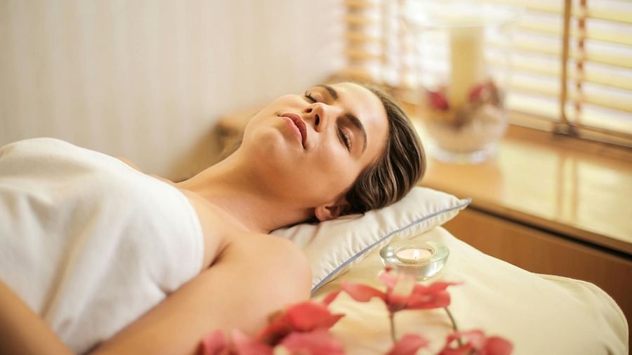 a lady laying on a bed with flowers and eyes closed after a rejuvenating massage