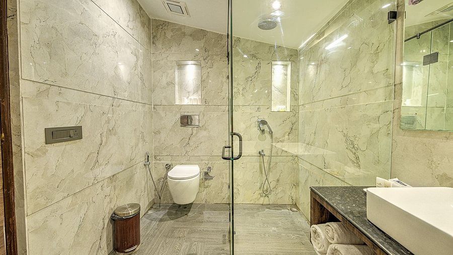 Modern and luxurious bathroom featuring marble walls and flooring, a glass-enclosed shower area, and sleek contemporary fixtures.