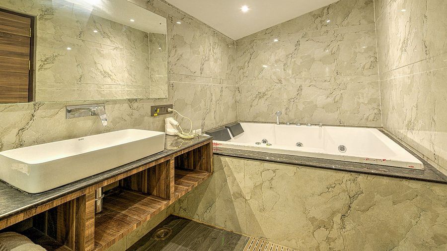 Elegant bathroom with a large marble bathtub, spacious countertops, and mirrored walls creating a refined and relaxing ambiance.