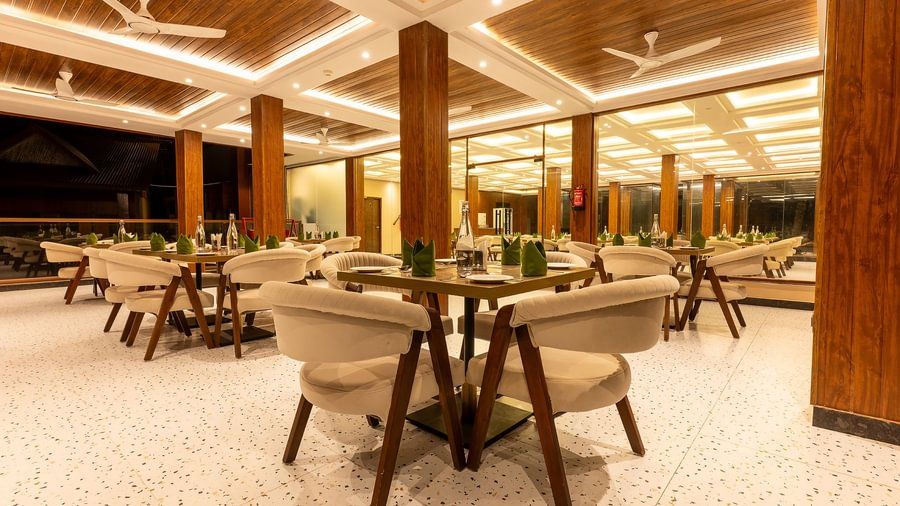 The resort's restaurant interior with light furniture, wood-panelled ceilings, and warm evening lighting.