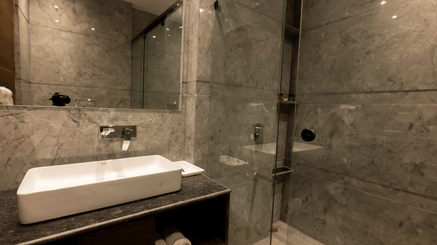 Clean modern bathroom with glass shower and washbasin at Silver Sand Sea Princess Beach Resort, Port Blair.
