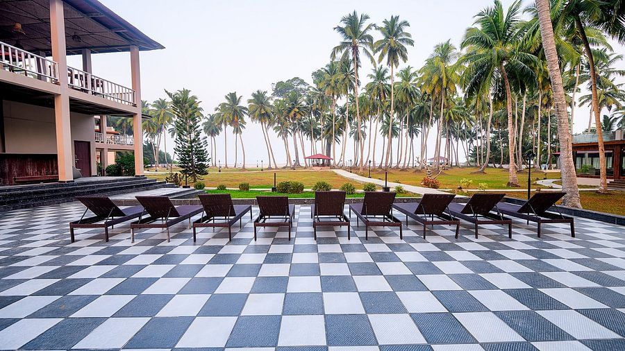 Outdoor seating arrangement with a serene view with coconut trees at Silver Sand Sea Princess Beach Resort, Port Blair
