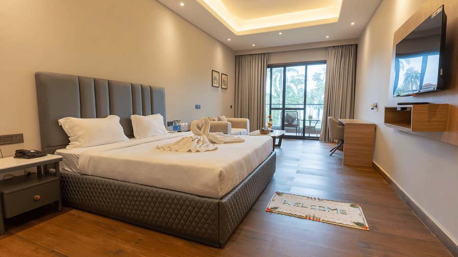 Spacious modern room with double bed, balcony view, and TV at Silver Sand Sea Princess Beach Resort, Port Blair.