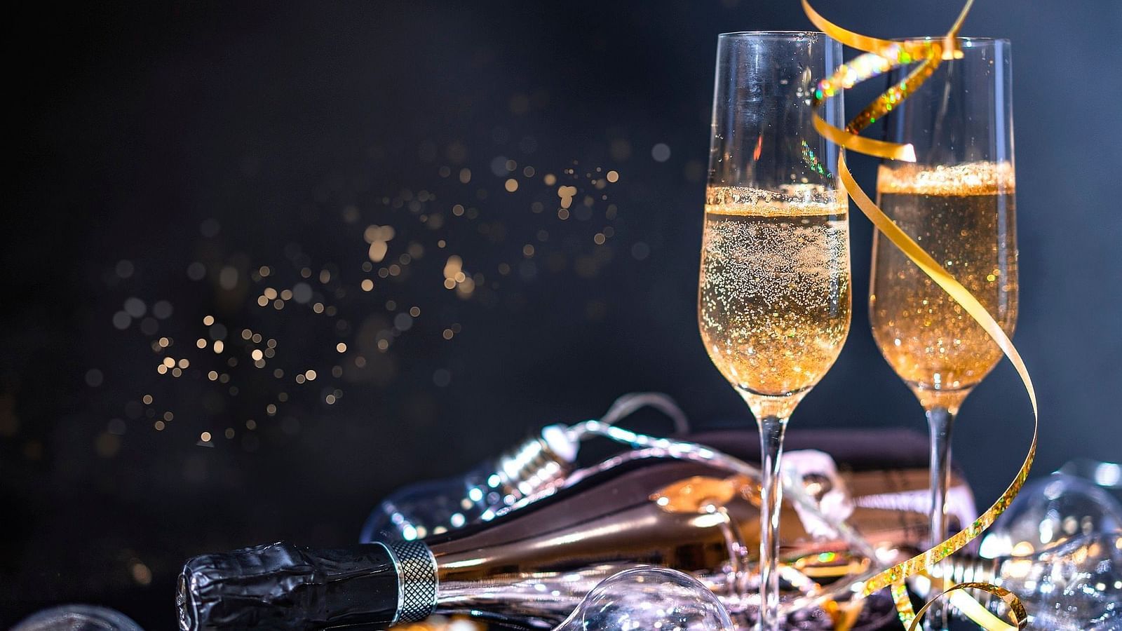 two champagne glasses and a bottle kept on a heap of confetti