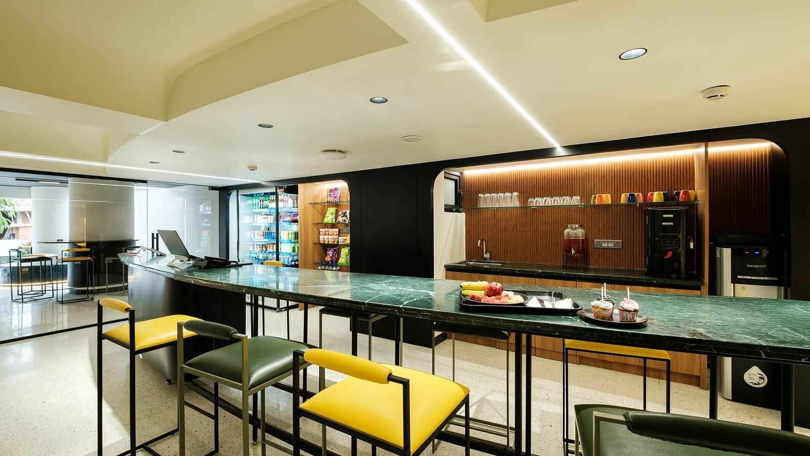 Common area at Indie Stays, Jaipur, featuring a large table surrounded by cushioned stools for comfortable seating.