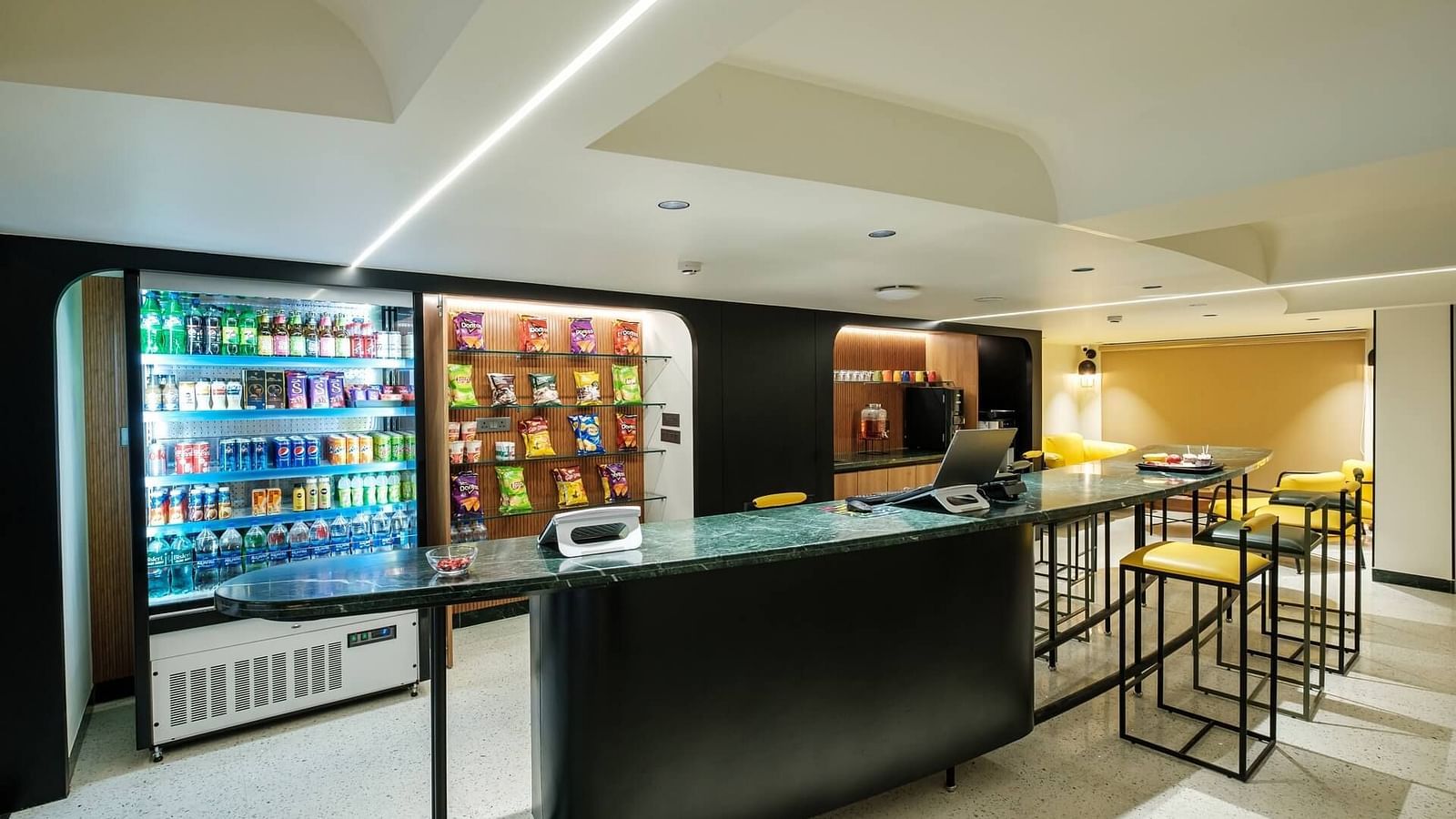 Vending machines at Indie Stays, Jaipur, stocked with snacks, alongside a large table and chairs placed in front for convenience.