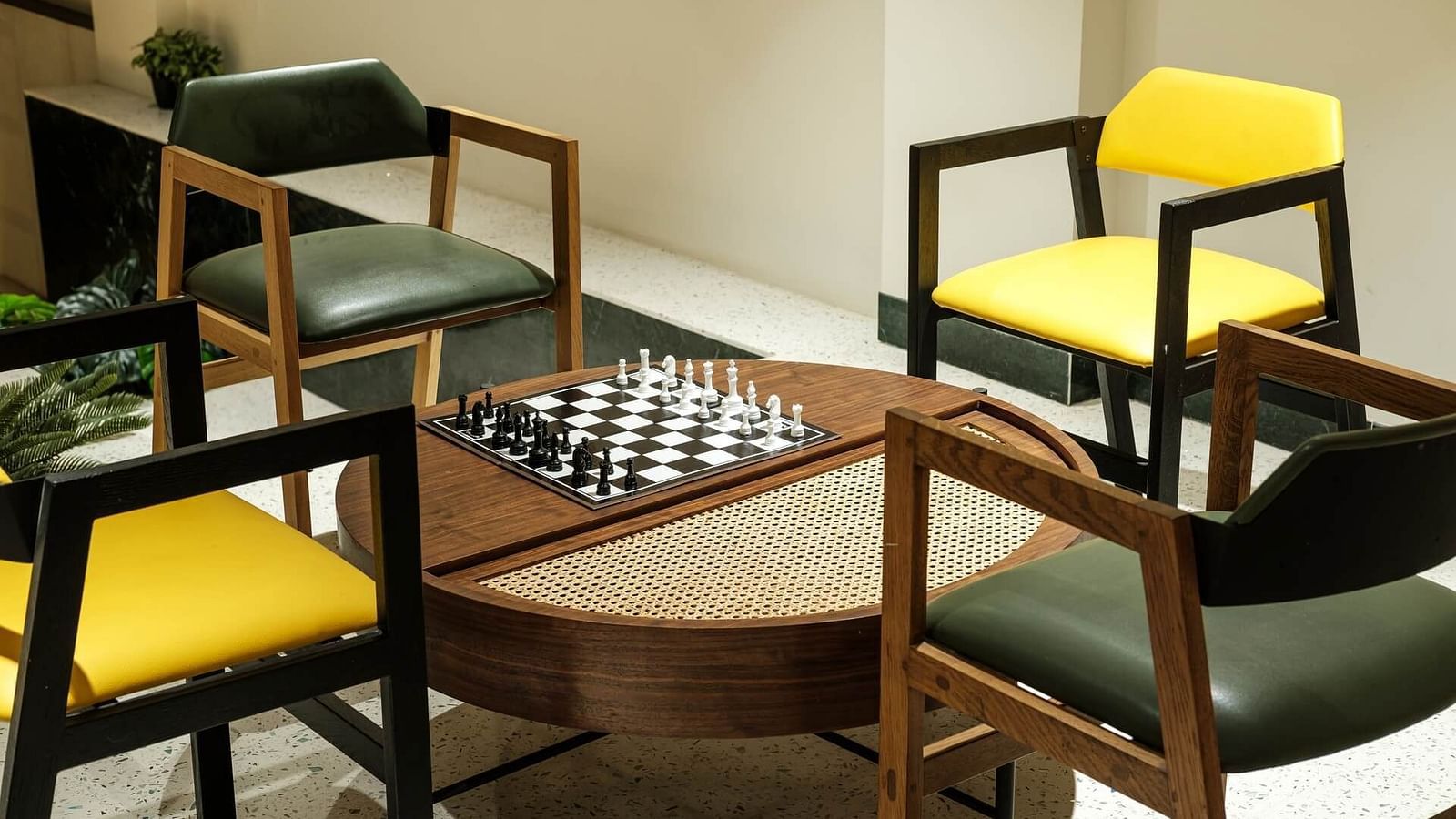 Circular wooden table at Indie Stays, Jaipur, with a chessboard on top and four chairs arranged around it.