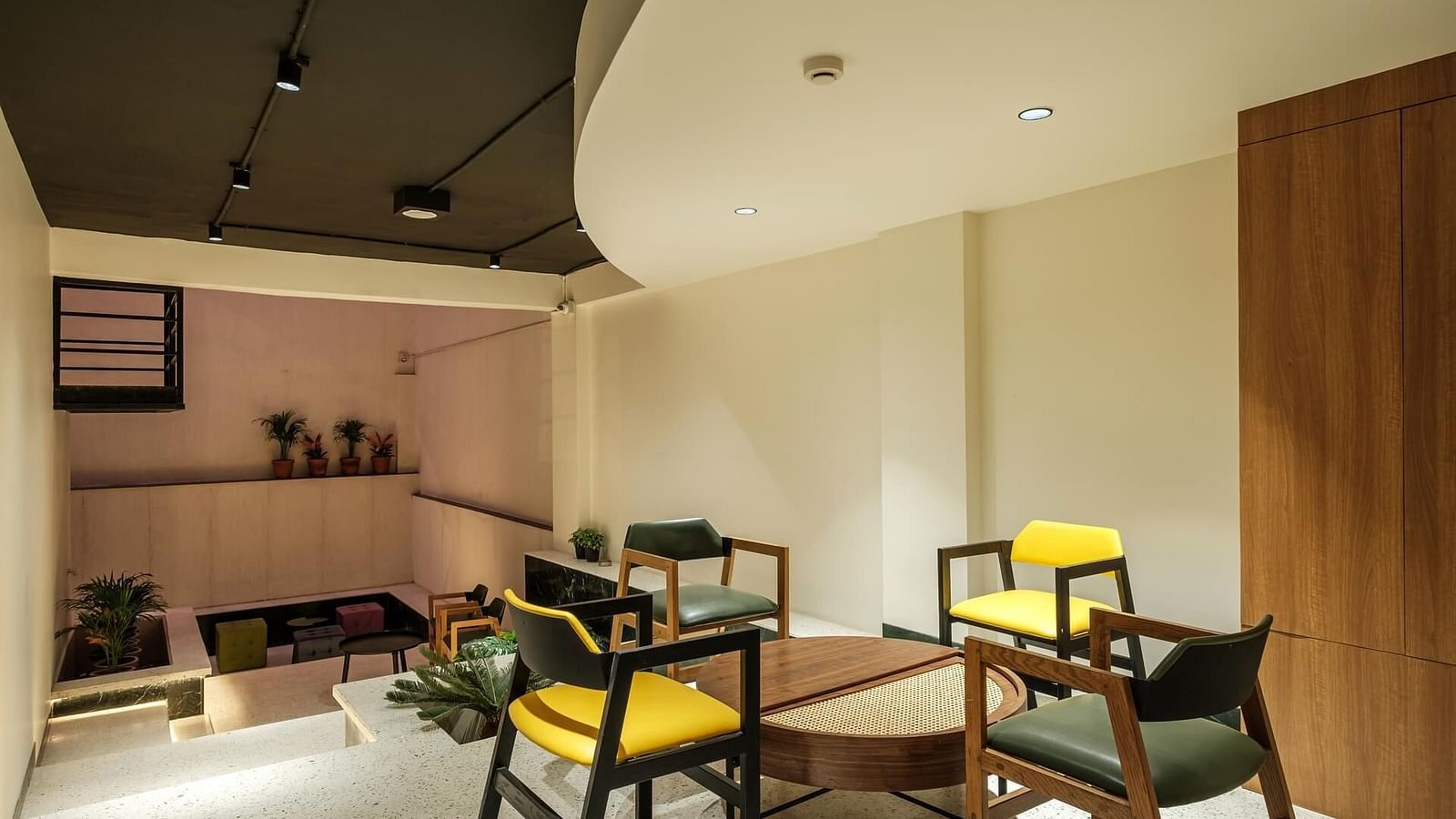 A circular wooden table at Indie Stays, Jaipur, surrounded by four chairs.