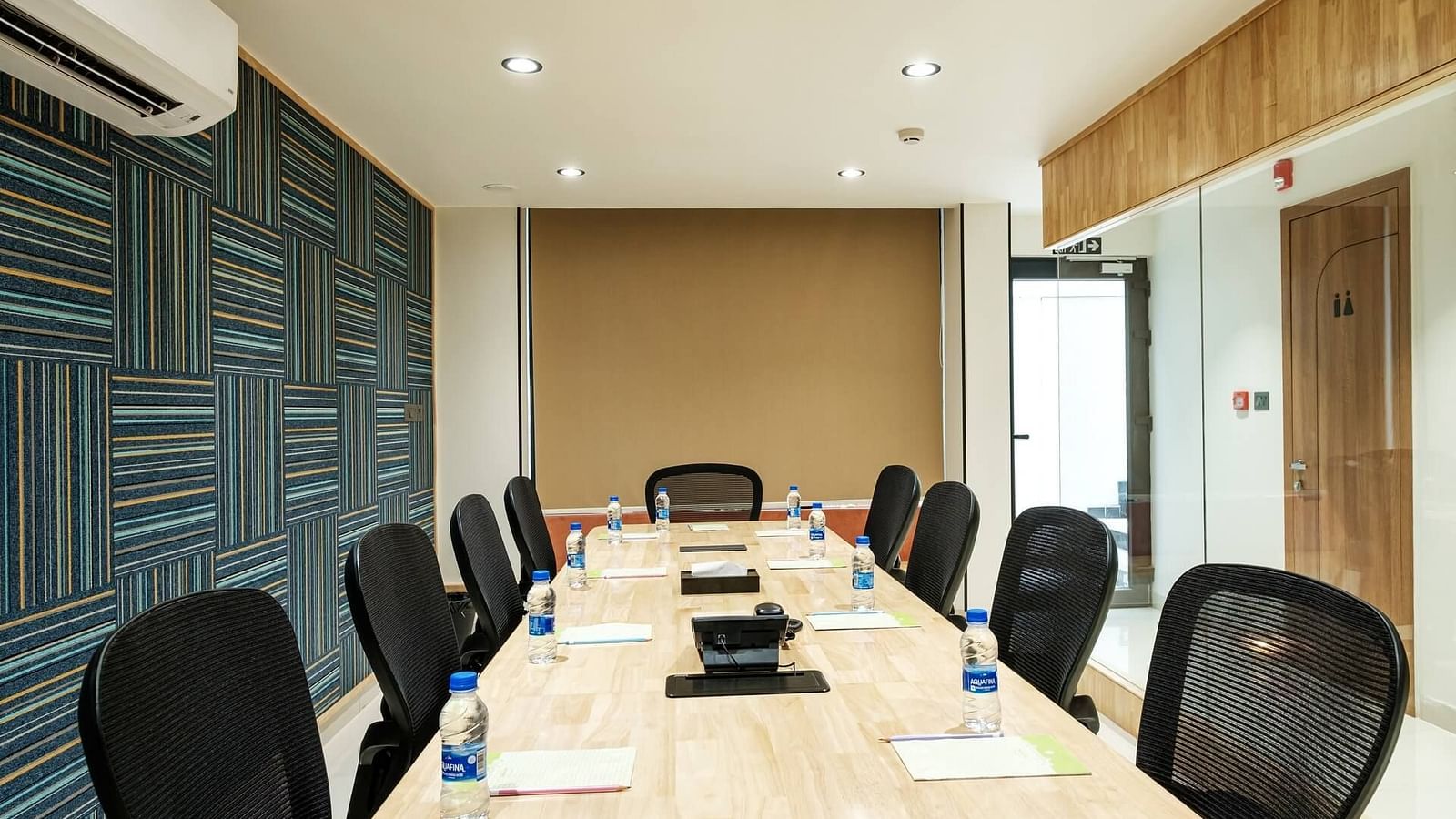 View of the full boardroom at Indie Stays, Jaipur, from the front, with chairs arranged along the sides and a wall-mounted AC.