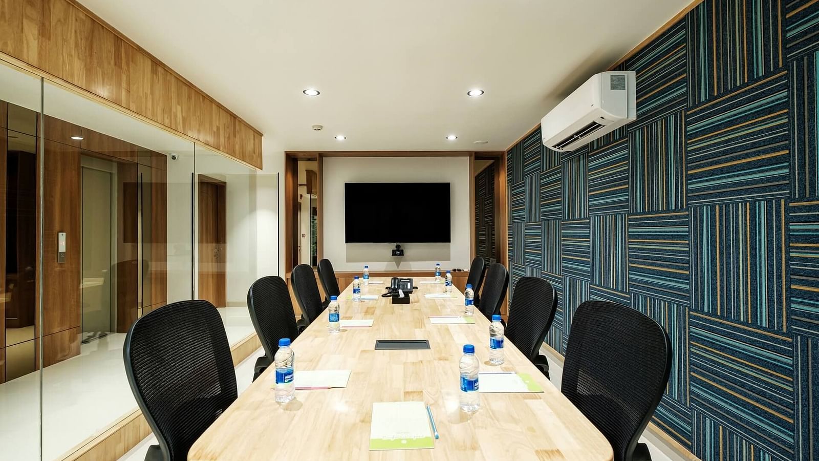  View of the full boardroom at Indie Stays, Jaipur, with chairs arranged along the sides, a screen at the front, and a wall-mounted AC.