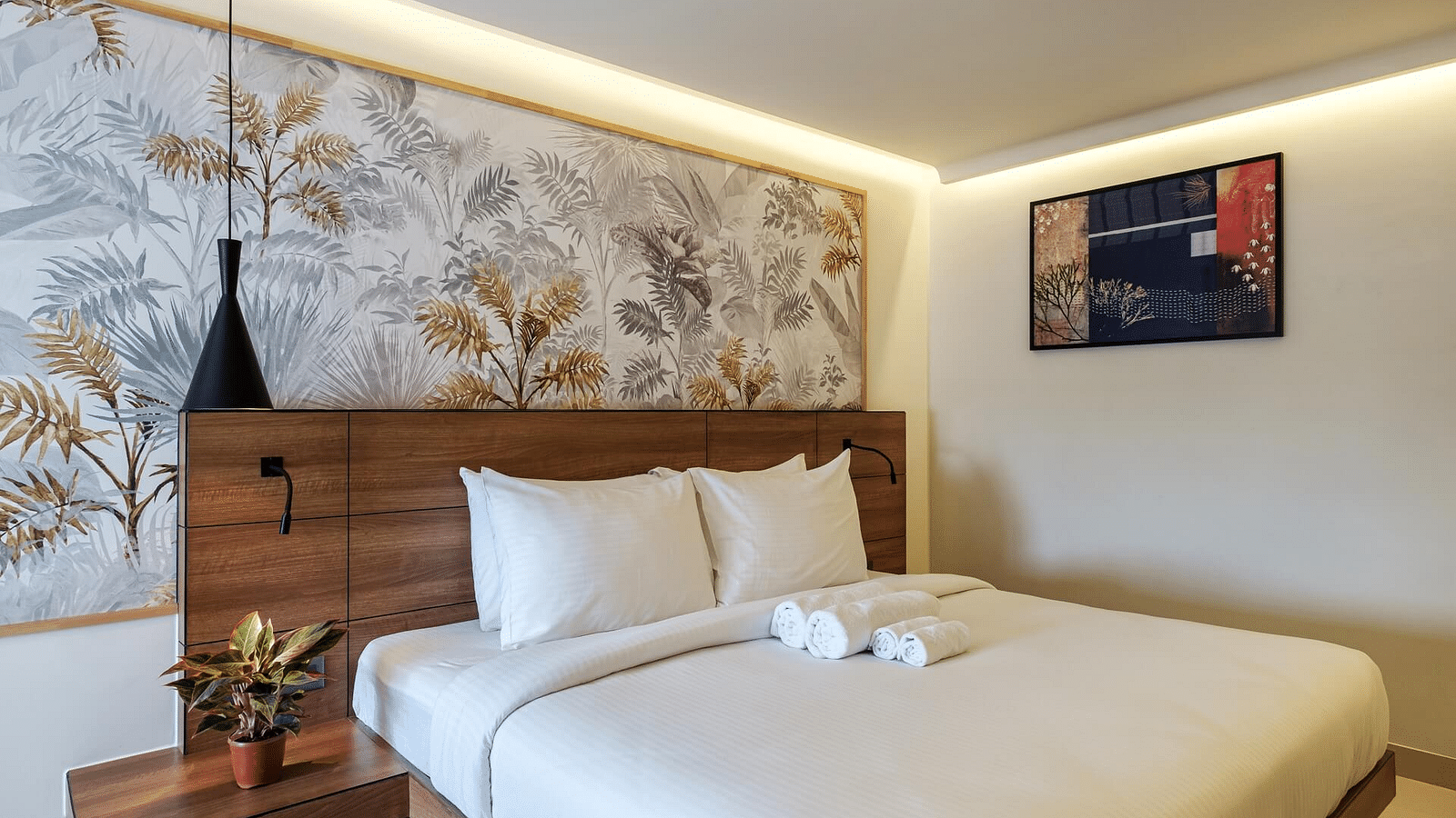 A spacious room at Indie Stays, Jaipur, featuring a large bed with a wooden headboard and warm lighting.