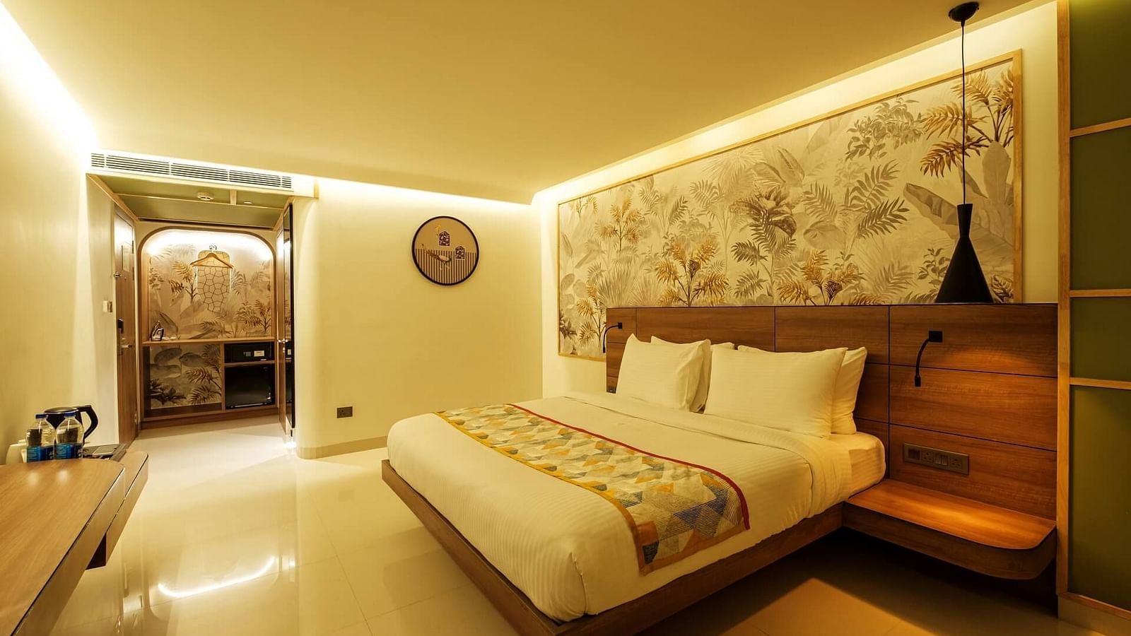 A spacious room at Indie Stays, Jaipur, featuring a large bed with a wooden headboard and warm lighting.
