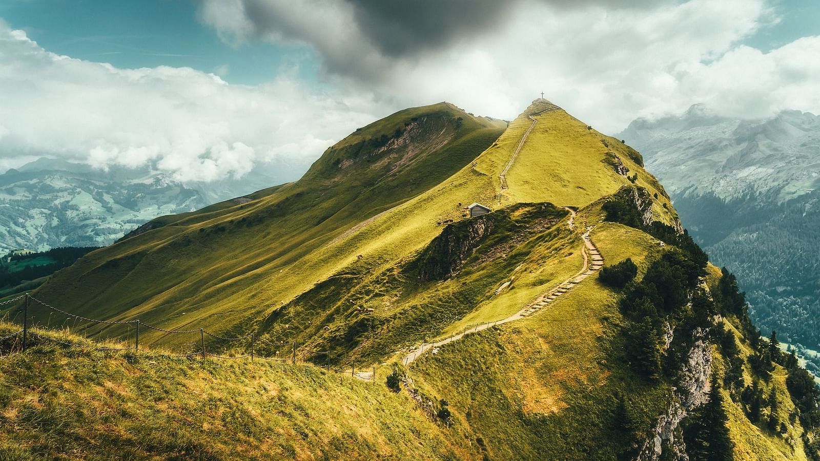 an image of a lush green mountain with clouds floating on top of it