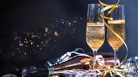 two champagne glasses and a bottle kept on a heap of confetti