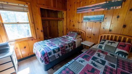 Twin bed cabin room with quilted bedding and wooden interiors at Kit Carson Lodge.