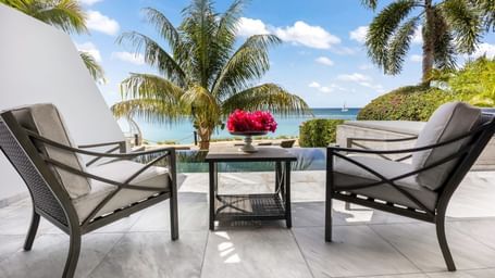 Two pool side lounge chairs placed overlooking the ocean
