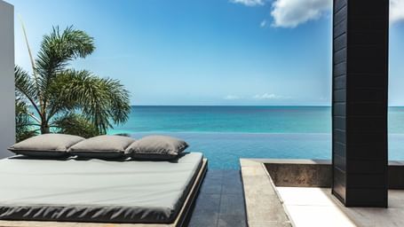 An infinity pool seamlessly blending in with the ocean stitched to the sky at Tamarind Hills, featuring pool side bed spaces 