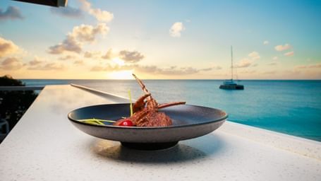 A gourmet dish served at sunset by the sea, with a yacht in the distance—perfect blend of fine dining and Caribbean tranquillity - Tamarind Hills Resort and Villas - Antigua