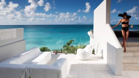 Woman on a terrace by the Caribbean Sea under a sunny sky.