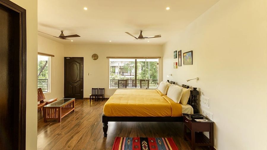 A bedroom with a bed, colorful rugs, and a view through a doorway.