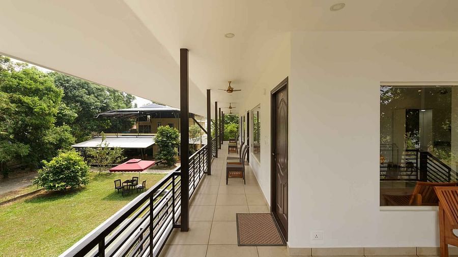 A long balcony or walkway with a view of lush greenery and possibly a body of water in the distance.