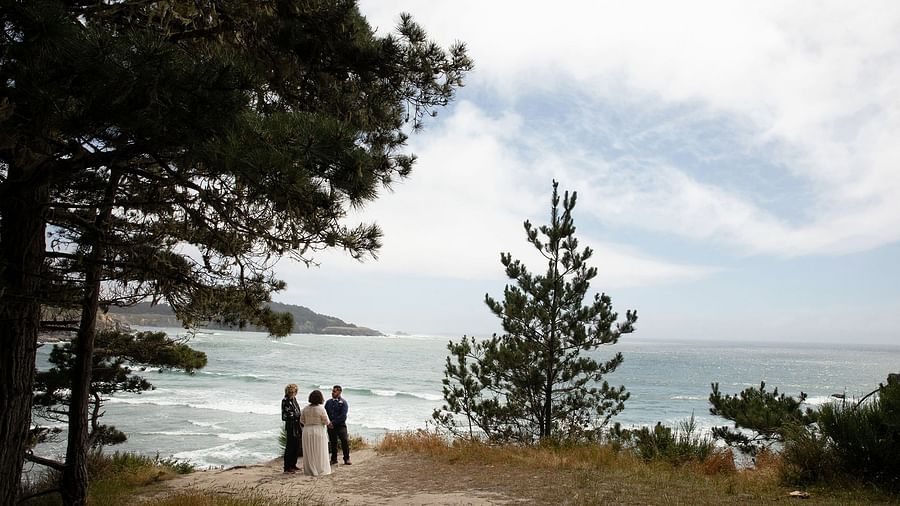 Couple exchanging vows on a cliff side with a panoramic ocean view