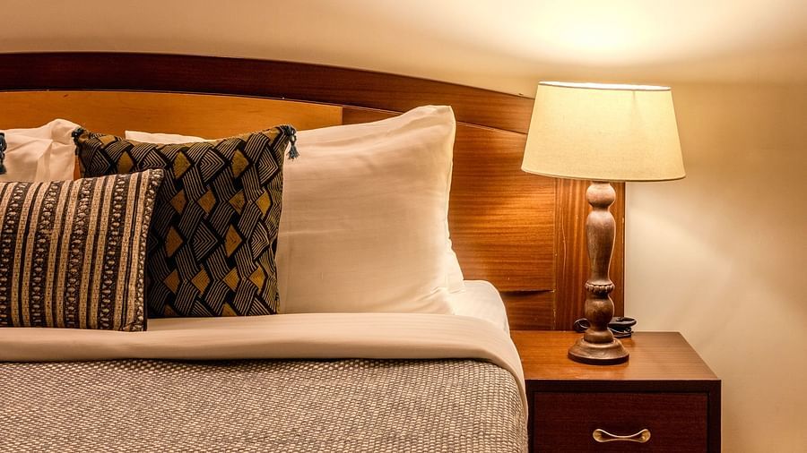 Pillows and duvet in a bed with wooden bed-post and side table with lamp on at The Conservancy Bungalow
