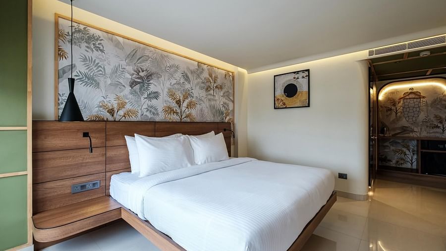 A spacious room at Indie Stays, Jaipur, featuring a large bed with a wooden headboard and warm lighting.