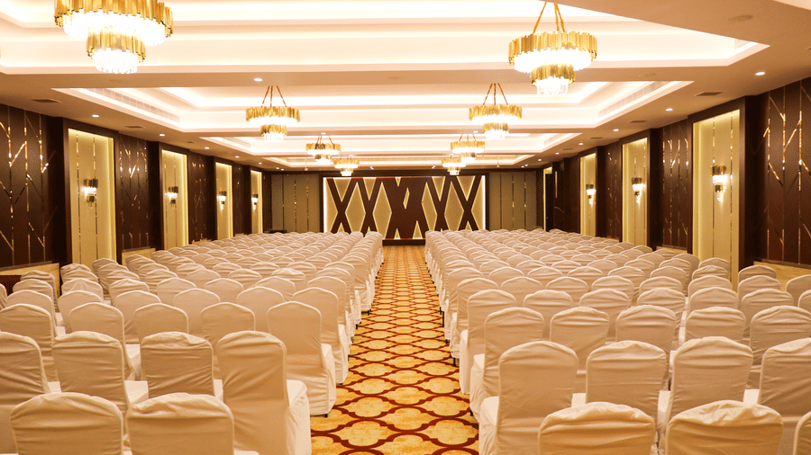 A symmetrical view of white-covered chairs arranged for a corporate conference or presentation - Jenneys Residency, Coimbatore