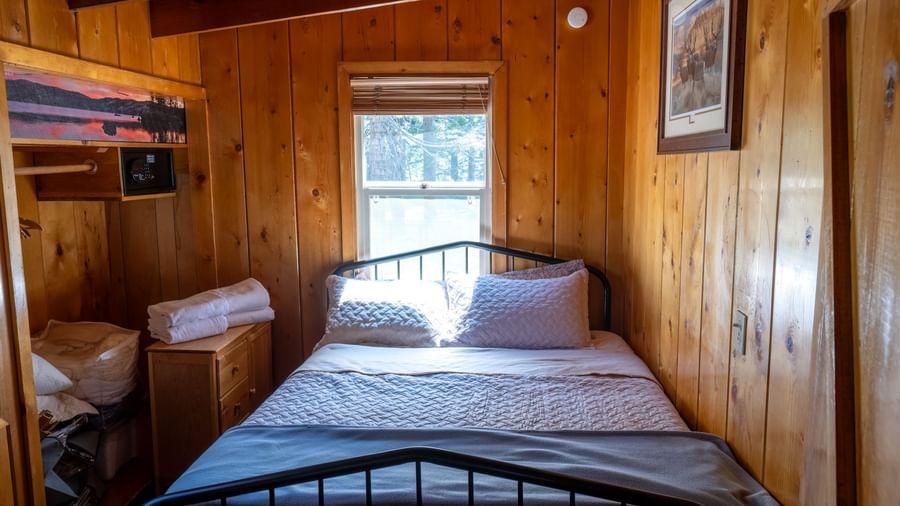 Cozy bedroom with wooden walls, metal bed frame, and warm lighting in a rustic cabin at Kit Carson Lodge.