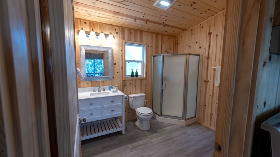 Spacious bathroom with full vanity, toilet, and shower in a warmly lit cabin at Kit Carson Lodge.