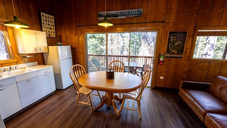 Kitchen and dining area with round wooden table, sofa, and forest views at Kit Carson Lodge.