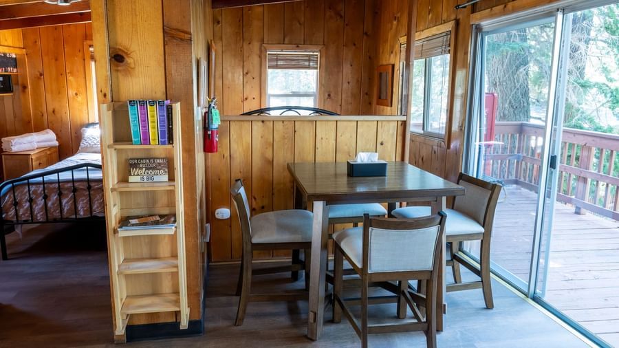 Dining area with sliding glass doors leading to the deck and forest views at Kit Carson Lodge.