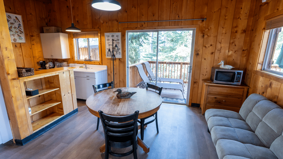 Cabin kitchen and dining space with round table, full stove, and large windows at Kit Carson Lodge