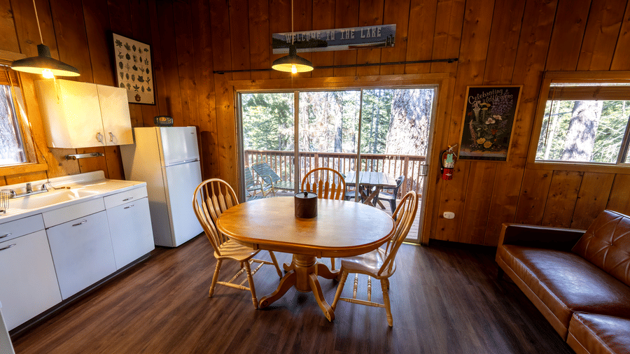 Kitchen and dining area with round wooden table, sofa, and forest views at Kit Carson Lodge