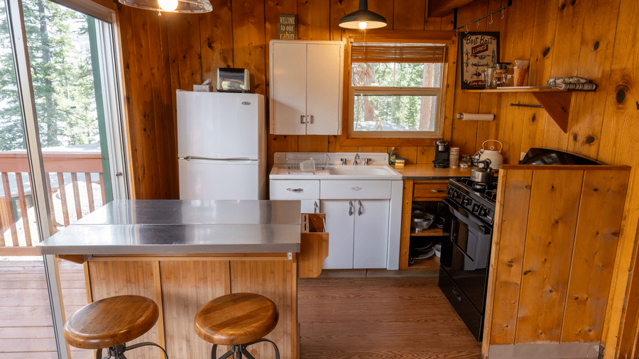 A kitchenette at Kit Carson Lodge equipped with a refrigerator, stove, and wooden breakfast counter with stools