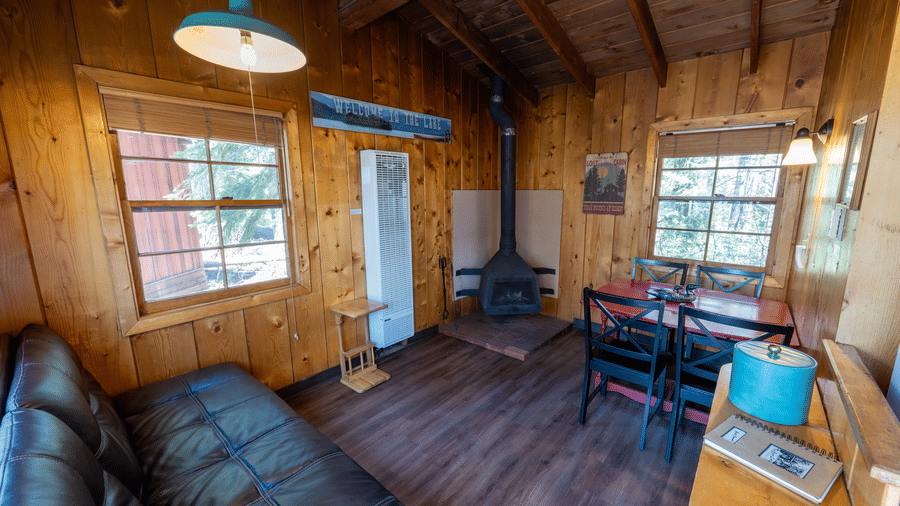 Living and dining space with couch, dining table, and wooden interiors in a rustic cabin at Kit Carson Lodge