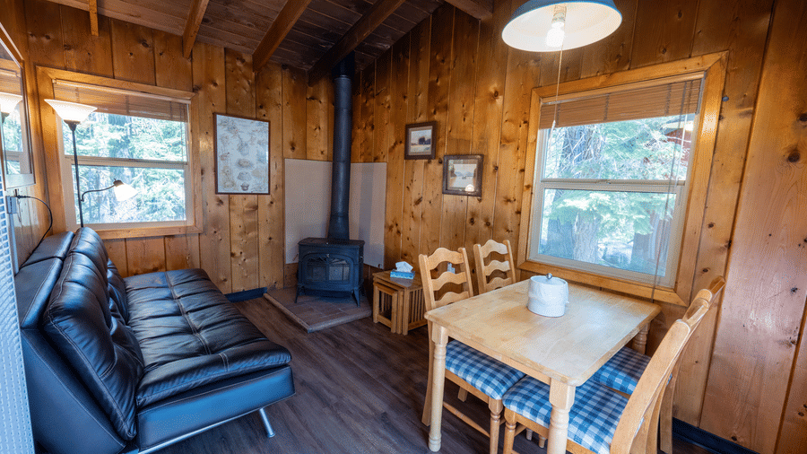 Cabin living room with cosy seating and dining table under wood-beam ceiling at Kit Carson Lodge