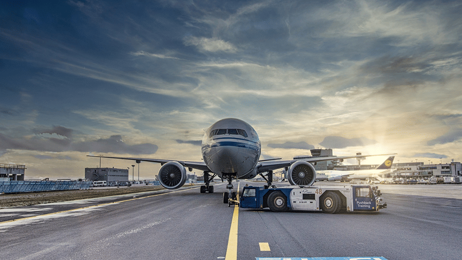 An aircraft parked on the tarmac at an airport under a cloudy evening sky