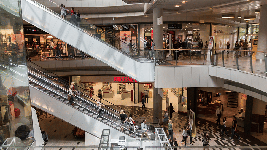 Shoppers and escalators across several levels inside a shopping mall