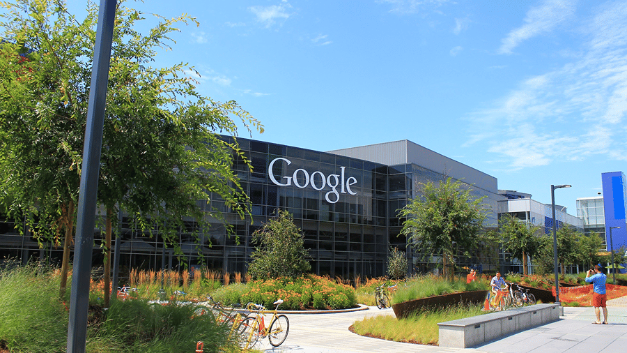 Google office building with its logo on the glass facade and landscaped grounds under a clear sky