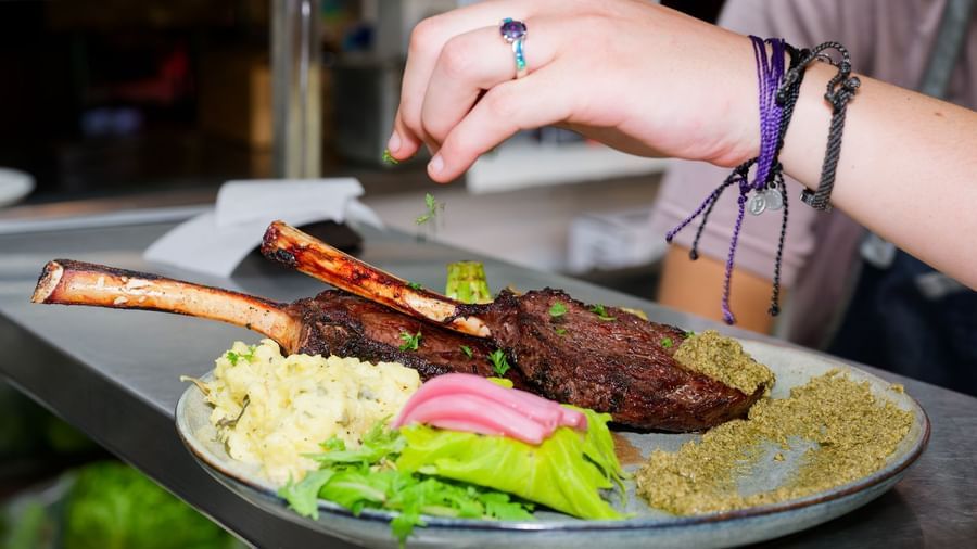 Lamb chops with couscous and greens being garnished before serving at Narrow Gauge Inn restaurant.