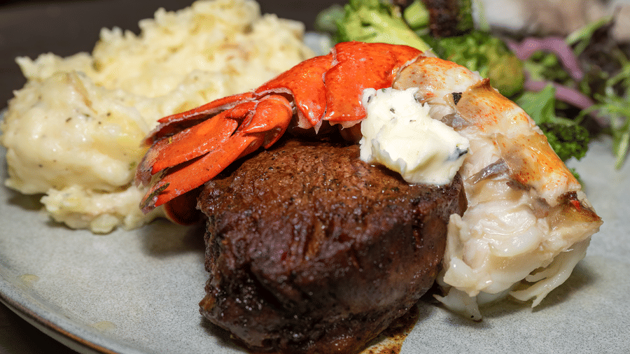 Surf and turf dish at Narrow Gauge Inn with steak, lobster tail, mashed potatoes, and fresh greens.