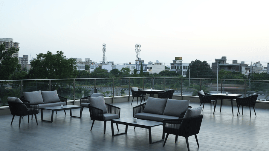 Outdoor dining seating area with tables and chairs overlooking the poolside at Ramada by Wyndham Sonipat Murthal.