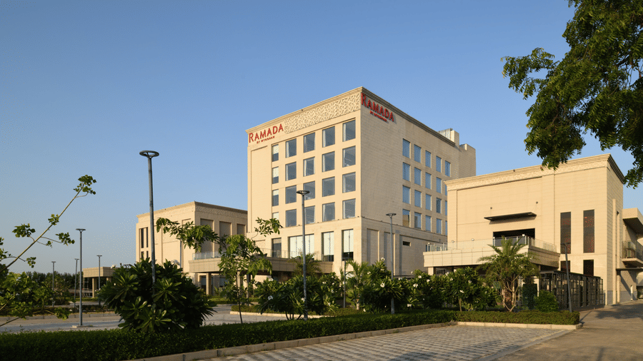 Daytime exterior view of Ramada by Wyndham Sonipat Murthal showcasing landscaped surroundings and contemporary architecture.